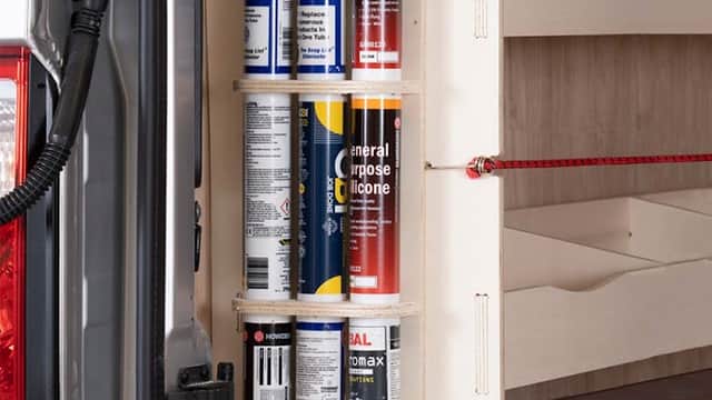 Vertical storage unit with various spray cans neatly organized in a van, showcasing racking and accessories for efficient use.