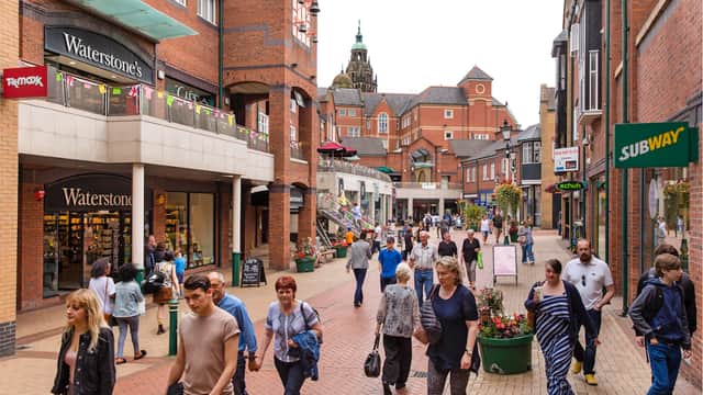 Busy shopping street in Orchard Square, Sheffield, featuring stores like Waterstone's and Subway, with people walking.
