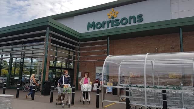 Morrisons storefront in Bessingby, Yorkshire, with shoppers and shopping carts outside.
