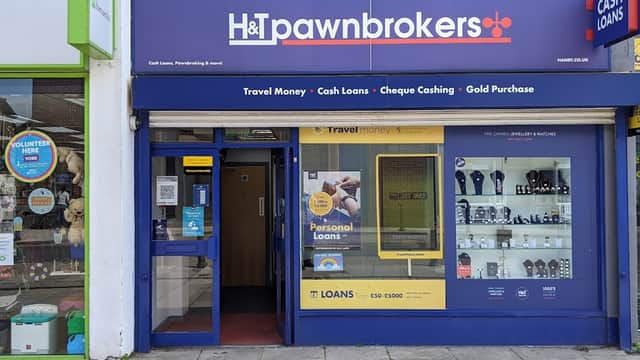 H&T Pawnbrokers storefront featuring signage for cash loans, travel money, and displays of jewelry and watches.
