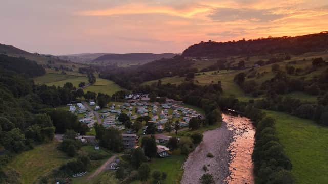 Aerial view of Swale View Caravan Park at sunset, surrounded by lush hills and a flowing river.