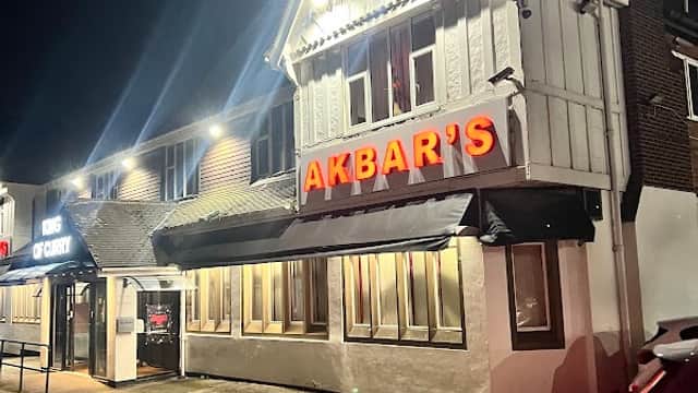 Brightly lit building with "AKBAR'S" sign, parked cars, and a dark night sky in Rotherham, Yorkshire.