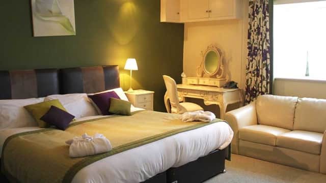 Cozy room with a large bed, green accent wall, elegant vanity, and soft lighting creating a warm atmosphere.