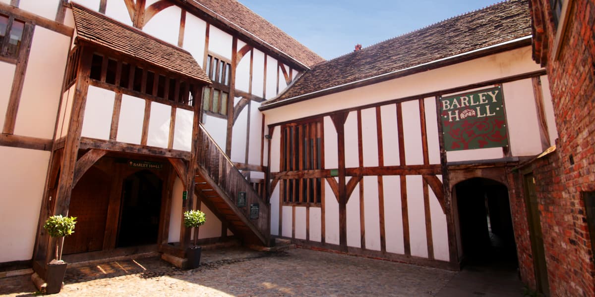 Tudor-style courtyard with timber-framed buildings, wooden staircase, and Barley Hall sign.