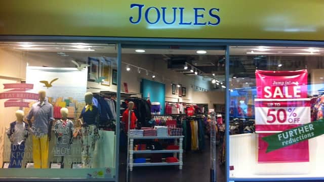 Bright storefront of Joules Outlet featuring clothing displays, mannequins, and a large sale banner.