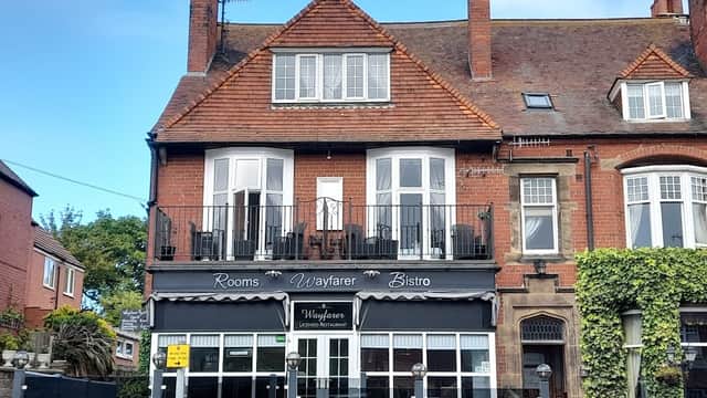 Victorian-style building with a balcony, featuring "Wayfarer" signage and outdoor seating in a quaint Yorkshire setting.