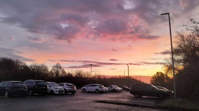 Fitzwilliam station car park at sunset, with parked cars and a colorful sky filled with clouds.