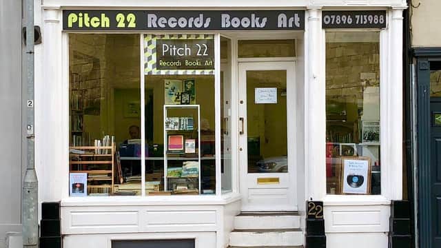 Storefront of Pitch 22 featuring records, books, and art, with large windows and a welcoming entrance.