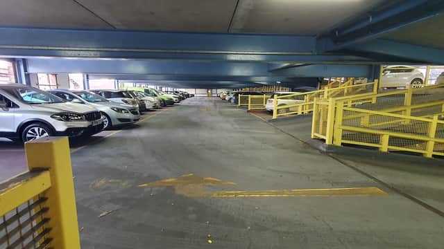 Multi-storey car park with parked cars, yellow barriers, and directional arrows on the ground in Rotherham, Yorkshire.