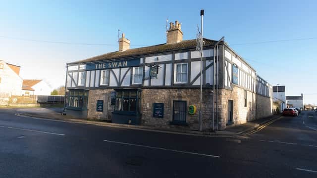 Historic building with a sign reading "The Swan," featuring a mix of stone and timber architecture in South Milford.