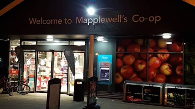 Co-op Food store in Mapplewell, Yorkshire, featuring a bright sign and apple-themed mural, illuminated at night.