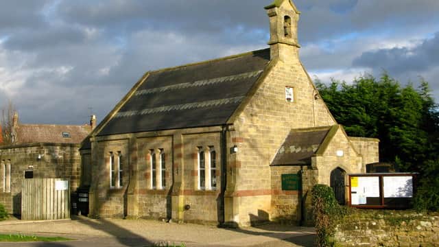 Rainton Village Hall, a stone building with a bell tower, surrounded by greenery and a gravel pathway.