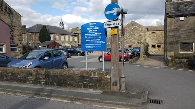 Clarke Lane Car Park sign with cars parked, buildings, and a one-way street sign in Meltham, Yorkshire.