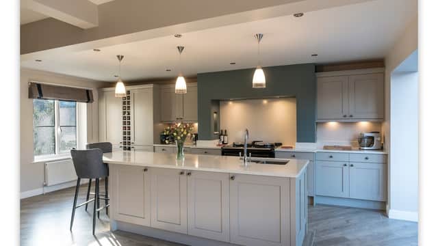 Modern kitchen with gray cabinetry, white countertops, pendant lighting, and a central island with bar stools.
