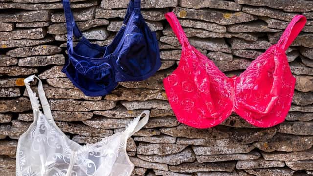 Three bras in navy, white, and pink displayed against a rustic stone wall in Old Byland, Yorkshire.