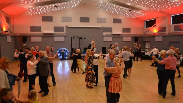 A lively dance event at Bubwith Leisure and Sports Centre, with people dancing under bright lights and a festive atmosphere.