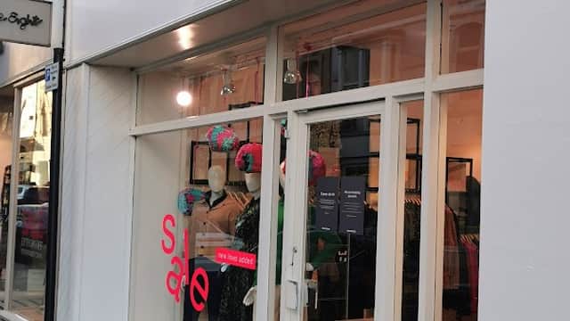 Clothing shop entrance with mannequins, sale sign, and modern window display in Harrogate, Yorkshire.