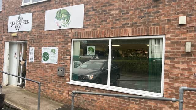 Brick exterior of a pet shop with large windows, signage featuring a chameleon, and a ramp for accessibility.