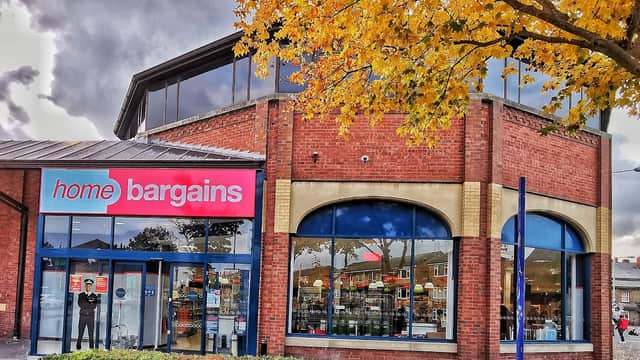 Red brick shop front with large windows, "home bargains" sign, and autumn leaves in the foreground.