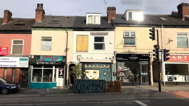 Colorful storefronts along a street, featuring "Gravel Pit Shop" with a mural and nearby businesses in Sheffield.