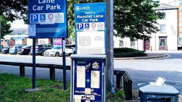 Welcome sign for Hunslet Lane Car Park, parking payment machine, litter bin, and trees in the background.