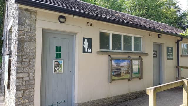Public toilets building with signs for men's and women's facilities, surrounded by greenery in Horton-in-Ribblesdale.