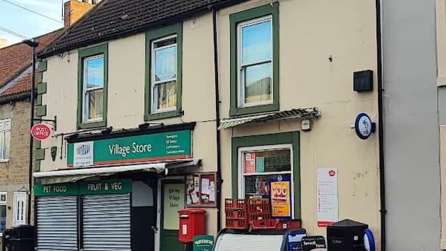 Barton Sub Post Office with green trim, signage for Village Store, and a red post box outside on a quiet street.