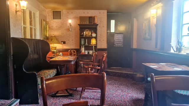 Cozy bar interior with patterned wallpaper, wooden tables, chairs, and a welcoming atmosphere in Follifoot, Yorkshire.