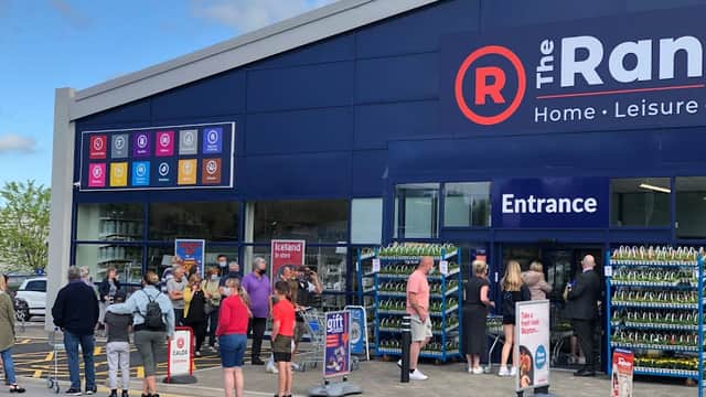 Crowd of people waiting outside The Range store in Bradley, North Yorkshire, with colorful signs and entrance visible.