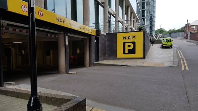 Multi-storey car park entrance with NCP signage, yellow accents, and a green vehicle parked nearby.