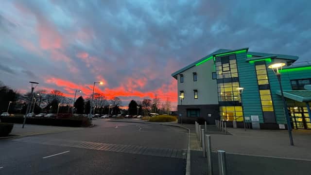 Selby War Memorial Hospital building with green accents, under a vibrant sunset sky and cloudy conditions.