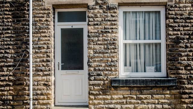 Stone facade of a terrace house with a white door and window, located in Hebden Bridge, Yorkshire.