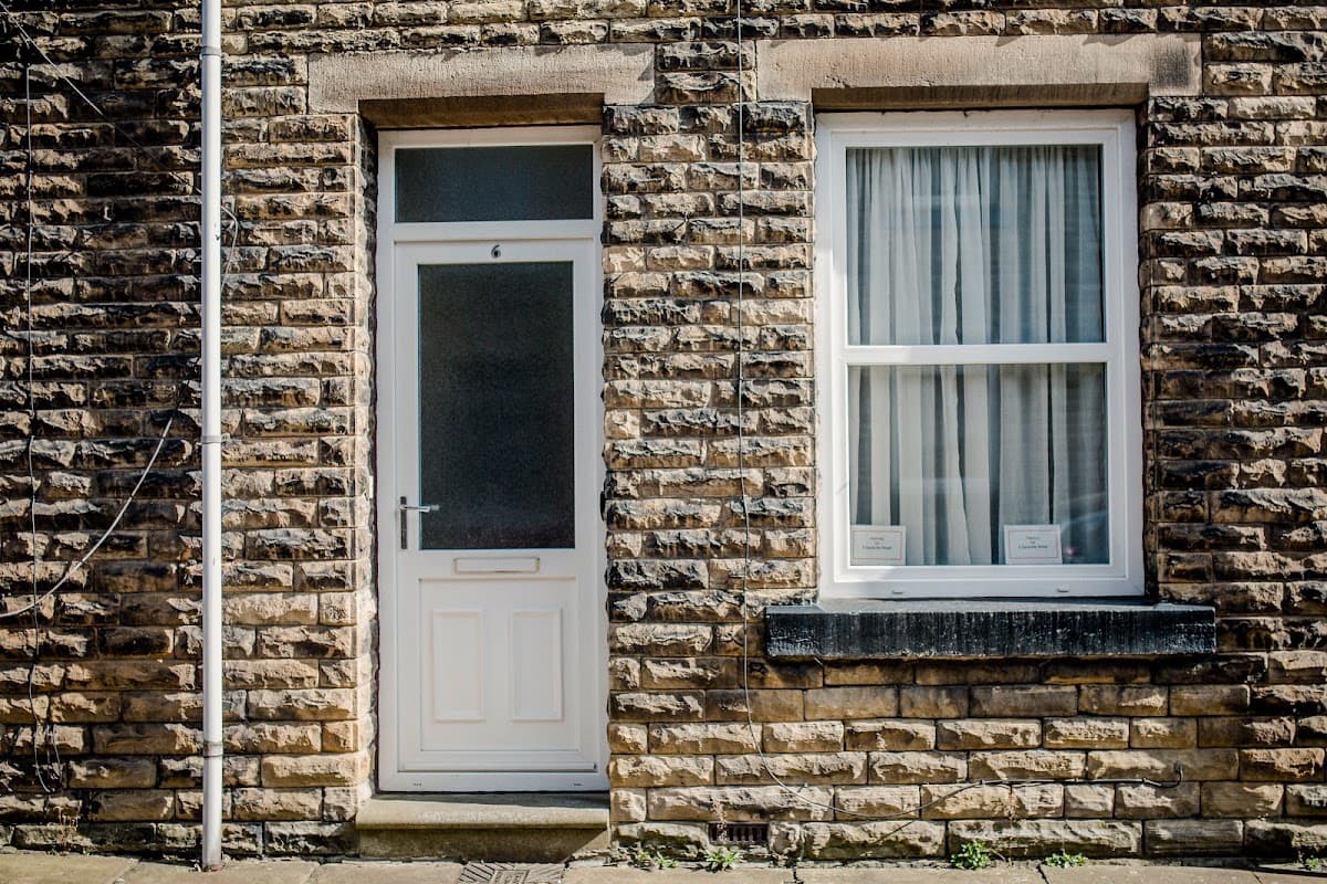 Stone facade of a terrace house with a white door and window, located in Hebden Bridge, Yorkshire.