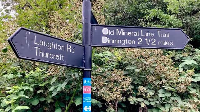 Signpost directing to Laughton Rd, Thurcroft, and the Old Mineral Line Trail, with greenery in the background.