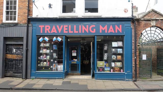 Bright blue storefront with "TRAVELLING MAN" in bold red letters, displaying books and colorful bunting.