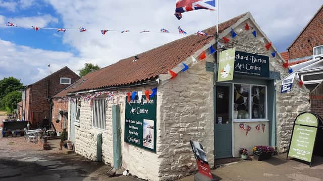 Quaint stone building with Union Jack flag, bunting, and art displays, located in Buckton and Bempton, Yorkshire.