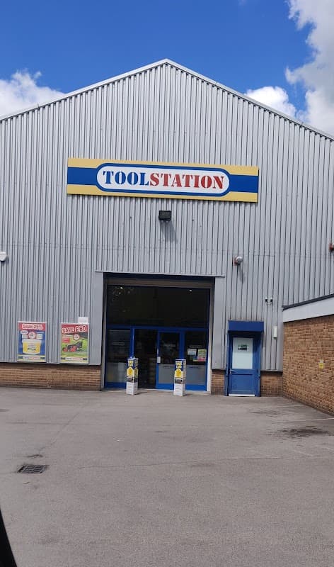 Toolstation storefront with a large sign, blue doors, and a grey metal exterior under a partly cloudy sky.
