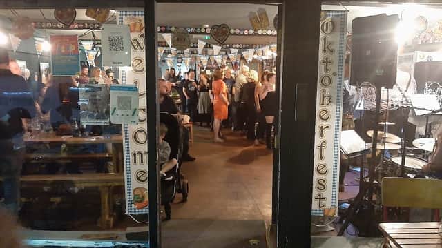 Entrance to The Crooked Tap, Acomb, bustling with patrons enjoying an Oktoberfest celebration, colorful decorations visible.