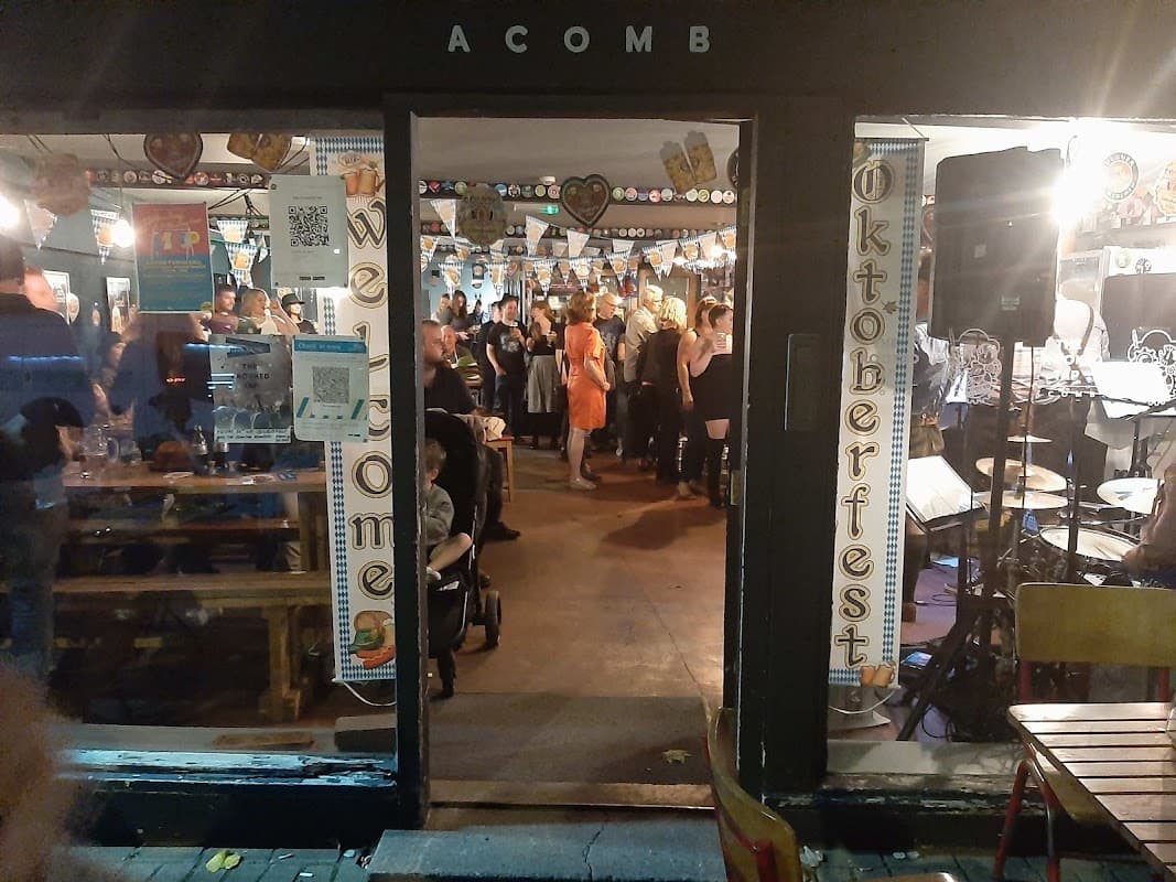 Entrance to The Crooked Tap, Acomb, bustling with patrons enjoying an Oktoberfest celebration, colorful decorations visible.