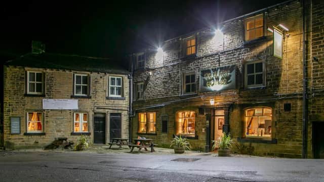 The White Horse hotel at night, featuring stone walls, illuminated windows, and outdoor seating.