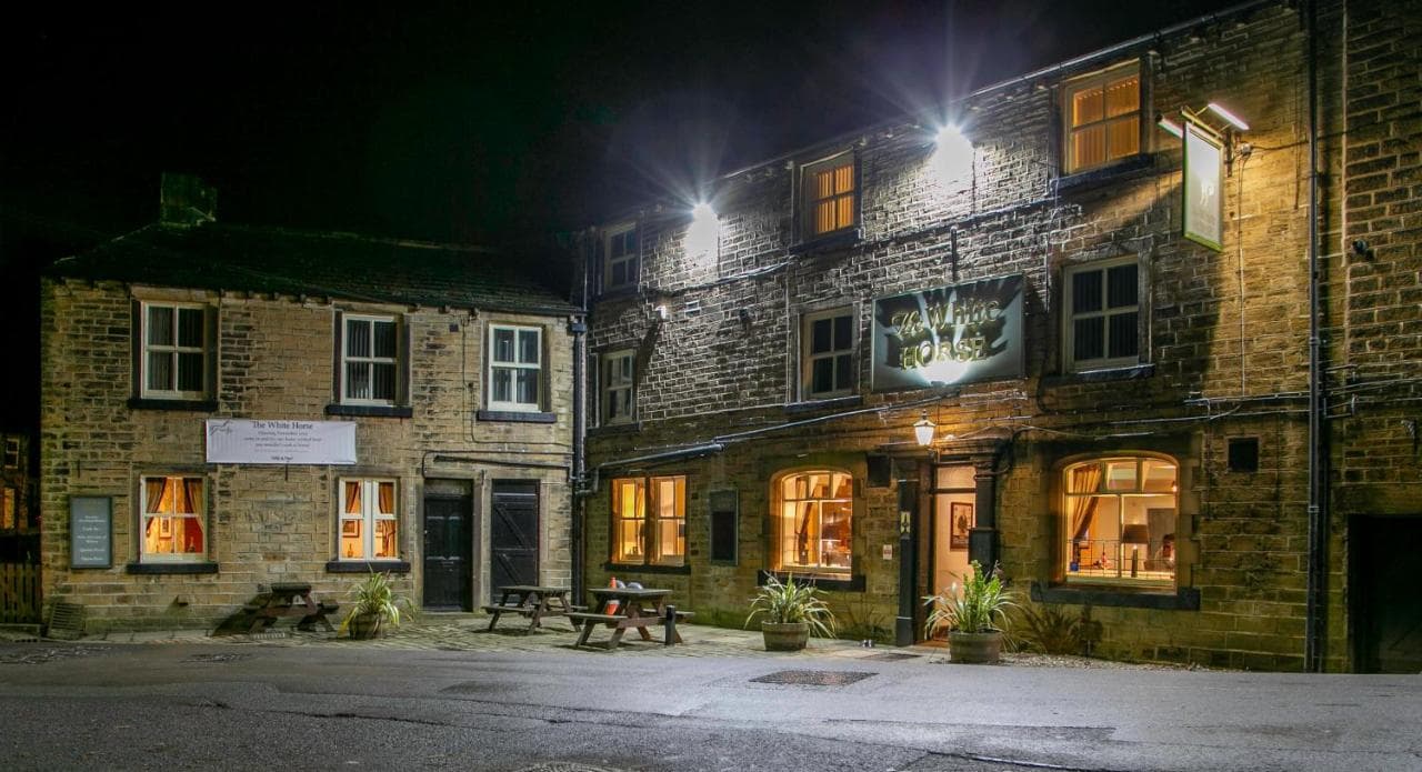 The White Horse hotel at night, featuring stone walls, illuminated windows, and outdoor seating.