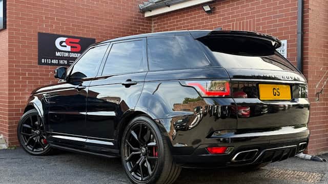 Black Range Rover Sport parked outside GS Motor Group Ltd shop, with a sign featuring the company logo on the wall.
