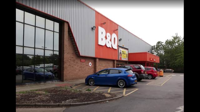 B&Q store exterior with parking area, featuring a blue car and several others, surrounded by greenery in Bridlington.
