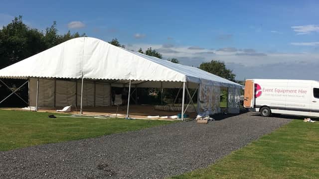 Large white marquee set up on a grassy area, with a delivery van parked nearby under a blue sky.