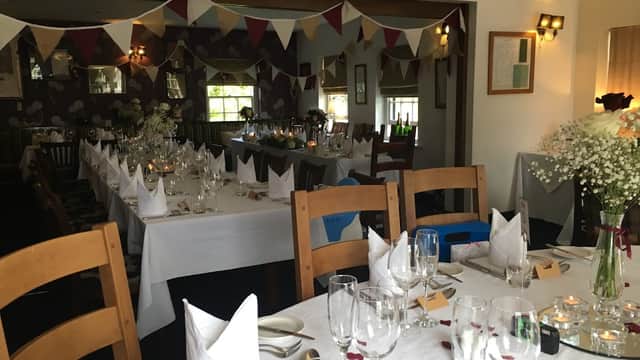 A cozy bar with tables set for dining, adorned with bunting and flowers, creating a festive atmosphere.