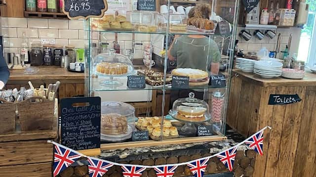 Display case filled with baked goods, Union Jack bunting, and a wooden counter in a cozy tearoom setting.