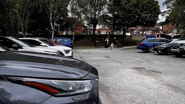 Car park with parked cars, trees in the background, and a cloudy sky over Wrenthorpe Park in Wakefield, Yorkshire.