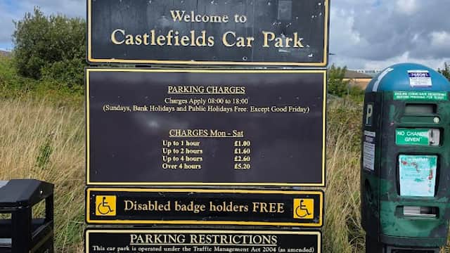 Welcome sign for Castlefields Car Park with parking charges, restrictions, and a nearby parking meter.