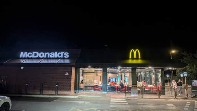 McDonald's restaurant at night, featuring a bright yellow logo and illuminated dining area with customers inside.