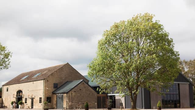 Stone buildings with large windows, a lush green tree, and a cloudy sky at Wharfedale Grange in Harewood, Yorkshire.